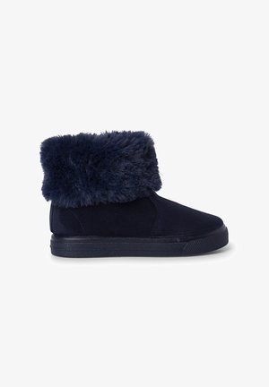 Botte mi-haute bleu foncé avec un large revers en fourrure épaisse et douce, tige façon suède, et semelle plate en caoutchouc noir.