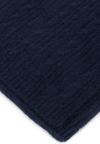 Ciemnoniebieski, dziany koc z teksturowanym wzorem z wypustkami, wykonany z miękkiego, puszystego materiału, zapewniającego ciepło i komfort.