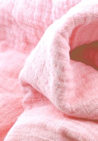 Helle rosa Stoff mit einer strukturierten, gewebten Musterung, die weiche, zerknitterte Schichten und ein durchscheinendes Erscheinungsbild aufweist. Geeignet für verschiedene textile Anwendungen.