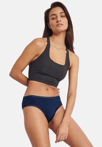 Sort crop top lavet af blødt materiale, kombineret med marineblå trusser med blonder langs linningen. Enkel og tætsiddende pasform.