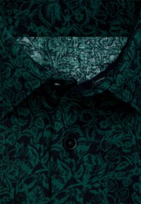 Camicia verde scuro con un motivo floreale, realizzata in tessuto testurizzato. Presenta un colletto a punta e un unico bottone nero.