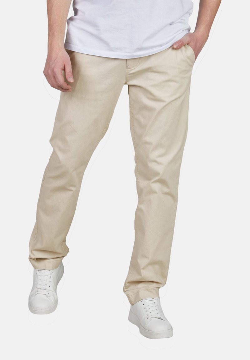 Beige Chino-Hosen mit geradem Bein, gefertigt aus Baumwollmischgewebe; kombiniert mit weißen Sneakers für einen lässigen Look.