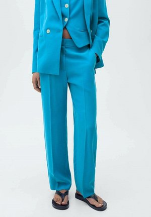 Costume ajusté turquoise avec une veste cintrée, un pantalon assorti et un tissu léger. Présente des boutons minimalistes et des poches latérales.