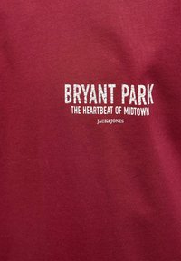 Bordeauxfarvet bomulds t-shirt med hvid trykt tekst: "BRYANT PARK THE HEARTBEAT OF MIDTOWN JACK&JONES" i en fed, struktureret skrifttype.