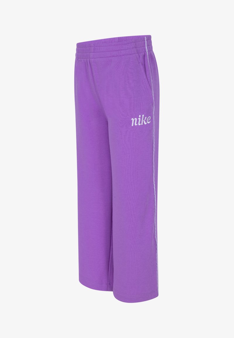 Lila Nike-joggingbyxor med elastisk midja, sidofickor och vit logotyp. Mjukt tyg med en avslappnad passform. Framträdande vita ränder på sidorna.