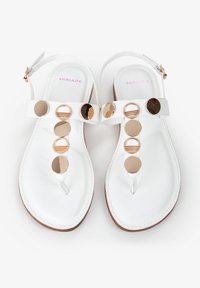 Witte sandalen met een platte zool, voorzien van ronde gouden accenten en een T-band ontwerp. Verstelbare enkelband, soepele textuur, minimalistische stijl.