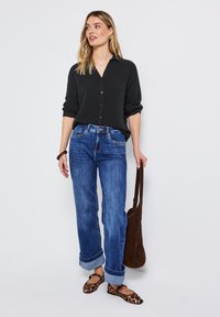 Svart skjorta med knappar, blå denimjeans med uppvikta ben, brun mockaväska och leopardmönstrade ballerina. Har en avslappnad passform och en vardaglig stil.