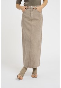 Falda larga de mezclilla beige con costuras delanteras y trabillas para cinturón. Cuenta con una cintura alta y un corte recto, que llega justo por encima de los tobillos.