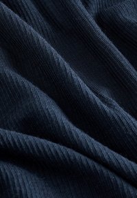 Tessuto di maglia blu marina scuro con una trama a coste, che mostra pieghe ondulate e leggere variazioni di tonalità e lucentezza.