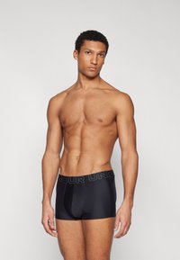 Zwarte boxershort met een brede elastische tailleband waarop "AMOUR UNDER" in grijze letters staat, met een soepele textuur en een aansluitend ontwerp.