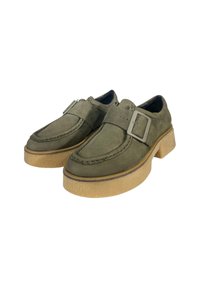 Chaussures vertes texturées avec détail de boucle, dotées d'une semelle épaisse beige et d'un design à bout rond. Le matériau supérieur est doux et lisse.
