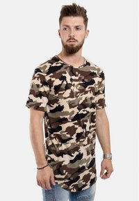 Camo t-shirt i beige, brunt och svart. Kortärmad, rund halsringning, mjukt material och avslappnad passform. Har ett kamouflage-mönster.