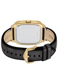 Boîtier de montre en acier inoxydable doré, forme carrée, bracelet en cuir noir avec perforations carrées et détails de boucle de couleur dorée.