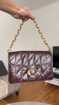 Burgundy nahkalaukku, jossa on tikattu kuvio, kultaketju kahva ja kultainen C-muotoinen lukko etupuolella.