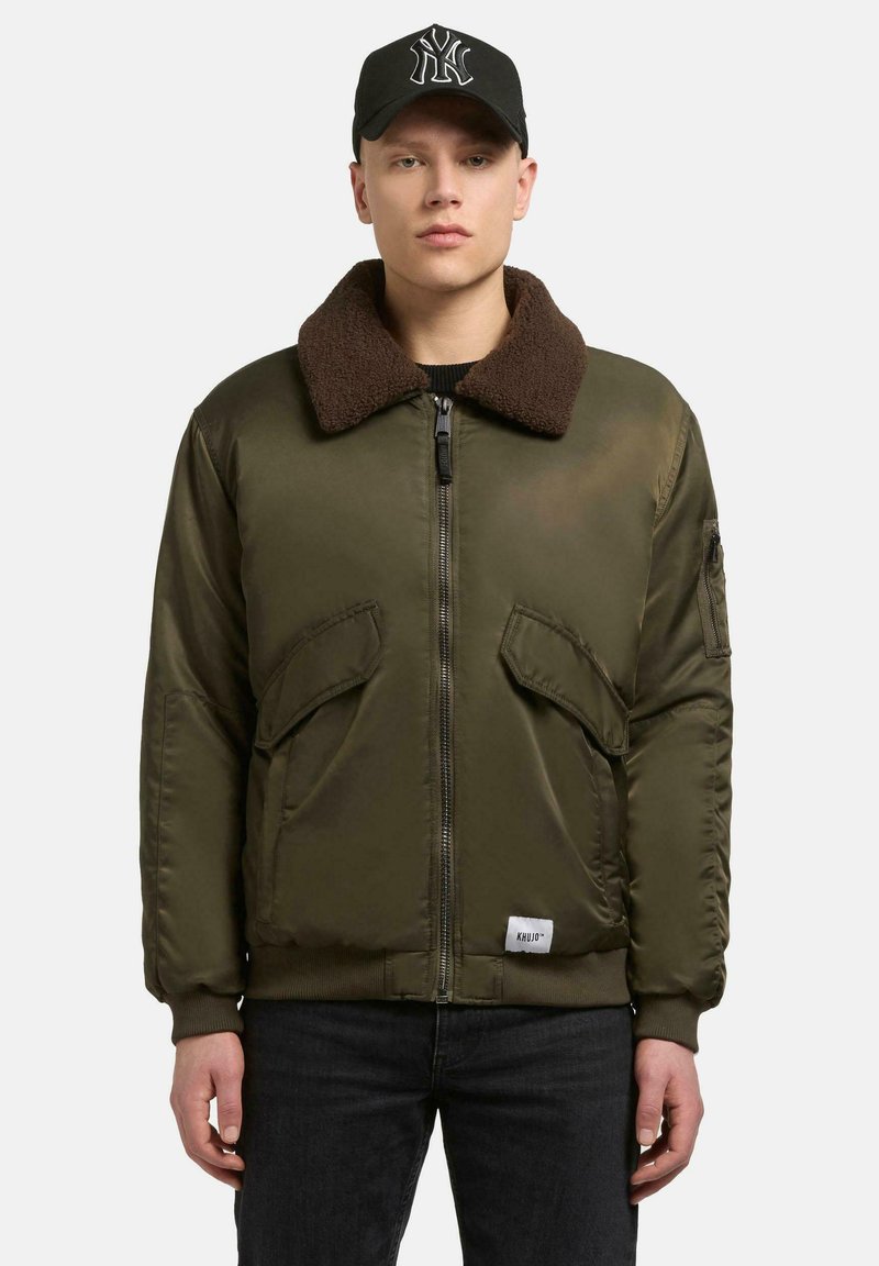 Olivgrüne Bomberjacke mit braunem Pelzkragen, Reißverschluss vorne, zwei großen Vorderentaschen und gerippten Bündchen, aus glattem Stoff gefertigt.