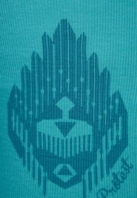 Turkusowa dzianina prążkowana z ciemnoturkusowym graficznym wzorem stylizowanego emblematem z geometrycznymi kształtami i liniami w centrum.