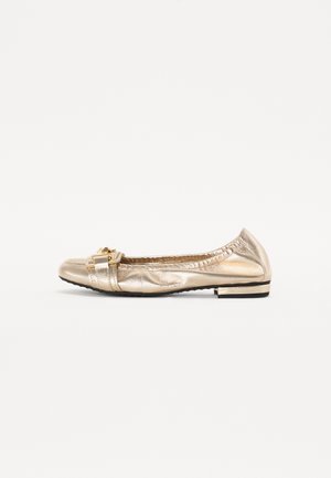 Ballerina in metallo dorato con punta tonda, superficie texturizzata, dettaglio decorativo a fiocco e piccolo tacco nero.