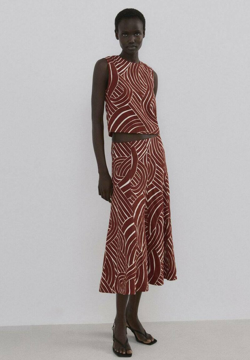 Zweiteiliges Outfit in Rot und Weiß mit Muster, bestehend aus einem ärmellosen Crop-Top und einem fließenden Rock mit wellenförmigem Design. Glatte Stoffstruktur.