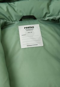 Zielona pikowana kurtka od wewnątrz z gładką teksturą oraz metką z logo marki "reima", rozmiar "128 / 8Y" i instrukcje dotyczące pielęgnacji.