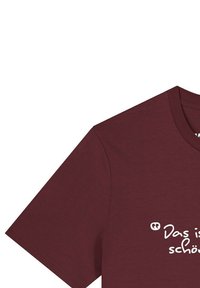 Bordeauxkleurig katoenen T-shirt met korte mouwen, met daarop in een casual scriptlettertype de witte tekst "Das ist schön" gedrukt aan de voorkant.