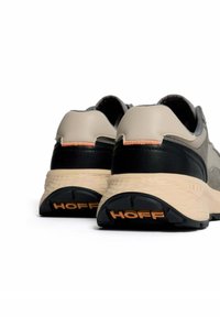 Zapatillas con un diseño en beige y negro, cuero texturizado y una suela ligera con el logo "HOFF" en naranja en el talón.