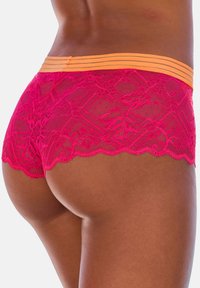 Rosenrote Spitzenboxershorts mit einem orange gestreiften Bund. Die Spitze weist florale und geometrische Muster mit gewellten Rändern auf.