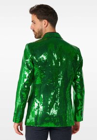 Blazer verde con paillettes, caratterizzato da una texture lucida, revers strutturati e maniche lunghe. Presenta paillettes in diverse sfumature di verde per un aspetto riflettente.