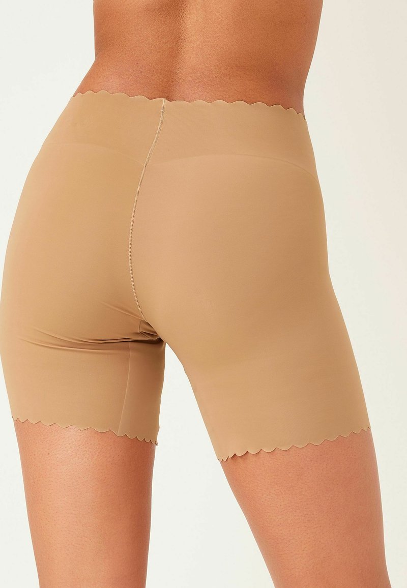 Naakte naadloze shorts met een gekartelde tailleband en een gladde textuur, ontworpen voor comfort en een discrete uitstraling onder kleding.