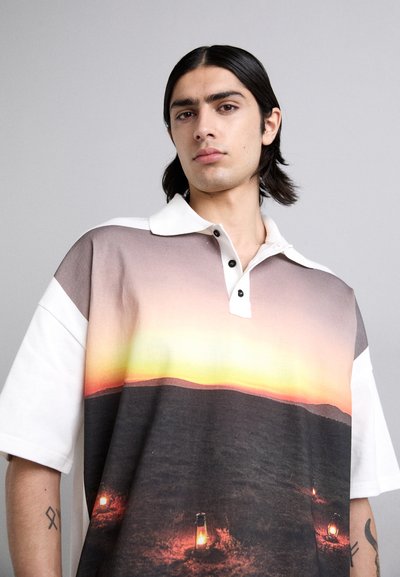 Polo à manches courtes avec un design de coucher de soleil en dégradé, présentant un col blanc, des boutons noirs et des détails de lanterne à l'ourlet.