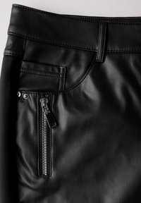 Zwarte faux leren broek met een gladde textuur, een voorzak en een zijrits met zilverkleurige hardware.