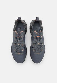 Mörkgrå sportskor med texturerat tyg, orange detaljer och snörningsdesign med förstärkt häl och dämpad sula.