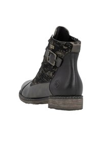 Bottine noire avec un mélange de cuir et de textile à motif. Elle possède un petit talon, un détail de boucle et un design à bout arrondi.