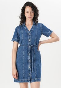 Denim srajčna obleka v svetlo modri barvi, ki ima gumbasto zapiranje spredaj, kratke rokave, ovratnik in pas s kravato ter vidne šive.