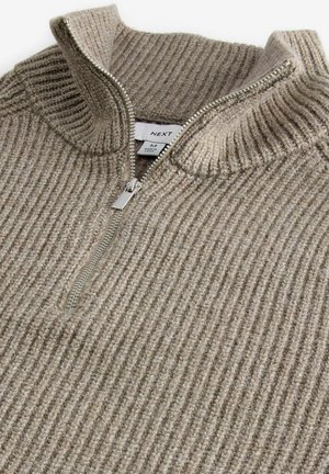 Bežový žebrovaný svetr s vysokým límcem a polovičním zipem. Vyrobený z texturovaného materiálu; obsahuje stříbrný zip a štítek uvnitř.