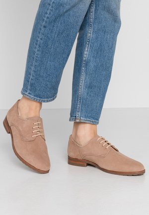 Beige suède veterschoenen met een ronde neus en een houten hak, aangevuld met lichte stiksels en een slank profiel.