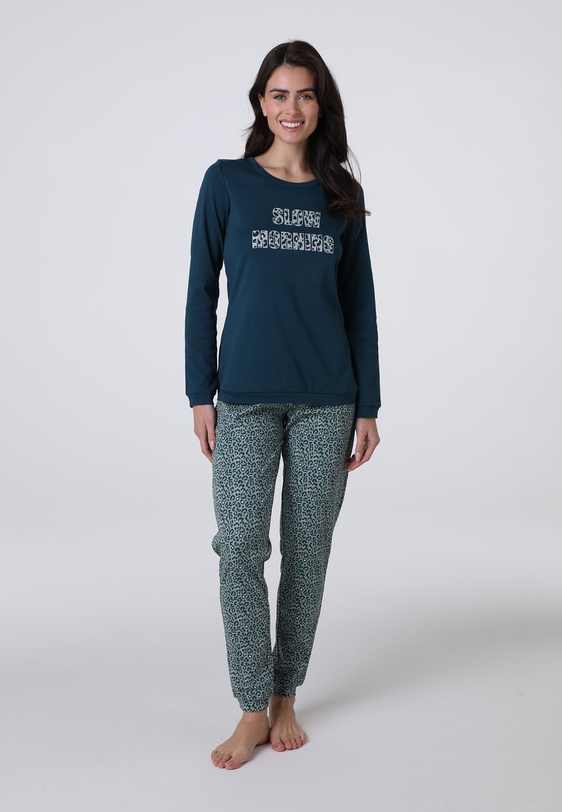 Maglietta a maniche lunghe di colore teal con la scritta "SLOW MORNINGS" e pantaloni da pigiama verdi a fantasia con design leopardato. Tessuto morbido, vestibilità rilassata.