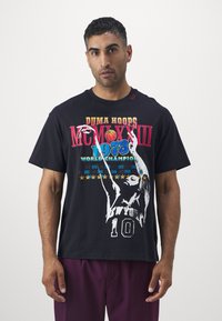 Zwart katoenen t-shirt met kleurrijke geprinte tekst en een afbeelding van een basketballer. Ontspannen pasvorm met korte mouwen en opvallende details.