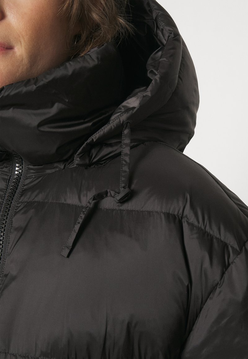 Schwarze Puffjacke mit hohem Kragen und Kordelzug. Strukturiertes Nylonmaterial, mit einem Reißverschluss und gestepptem Design.