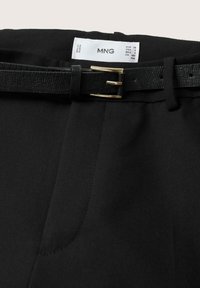 Pantalon noir avec une ceinture noire texturée dotée d'une boucle dorée et d'une étiquette de taille MNG visible à l'intérieur de la taille.