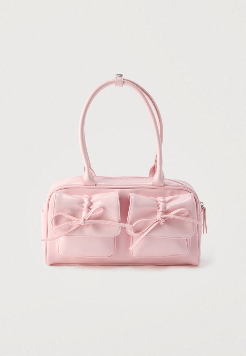 Bolso rosa con dos bolsillos frontales con lazos, fabricado en material sintético liso, y equipado con doble asa y cremallera.