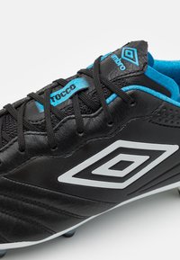 Scarpa da calcio nera con tomaia in pelle liscia, dotata di accenti blu e logo bianco, pannelli testurizzati e lacci neri.
