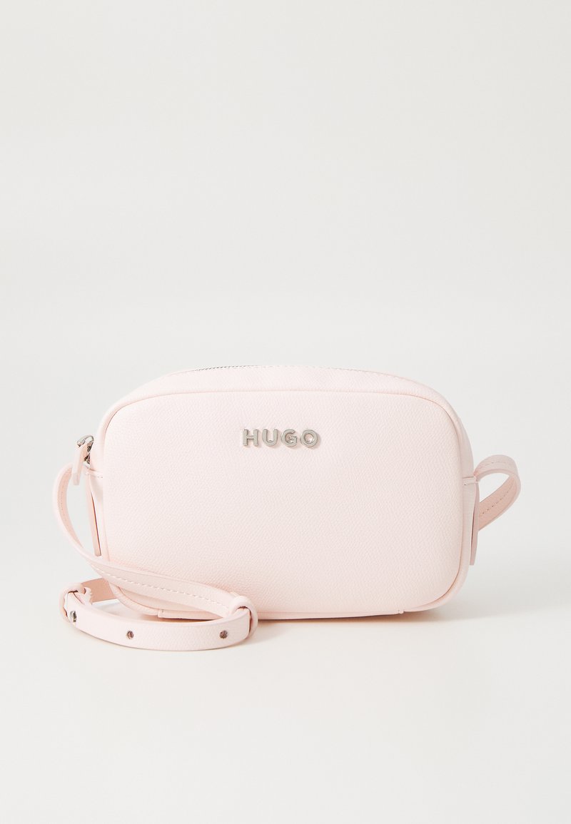 Borsa a tracolla sintetica rosa con texture, logo "HUGO" in argento, chiusura con zip e tracolla regolabile. Forma compatta e rettangolare.