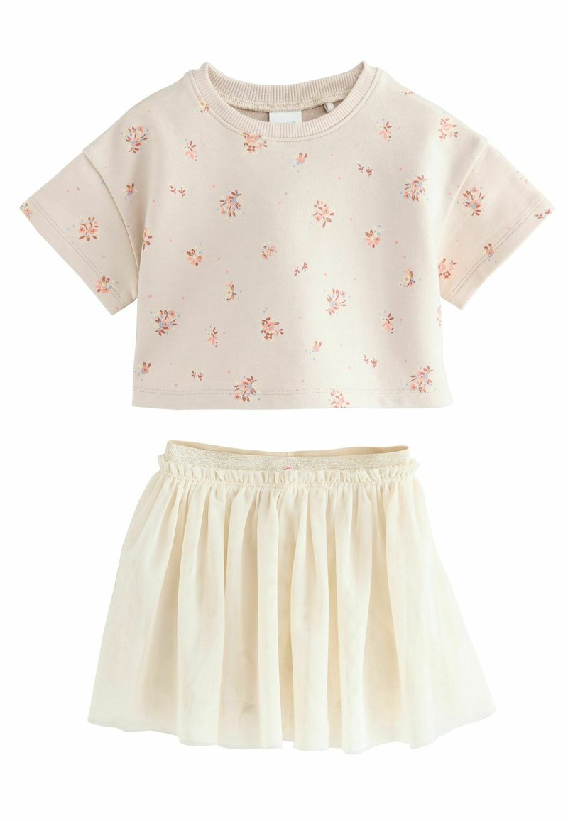 Kermakukkainen lyhythihainen paita, jossa on pastelinsävyisiä kukkia ja matching kermaiset pleat-hameet. Paidan pyöreä pääntie; hameessa on kimaltava vyötärönauha.