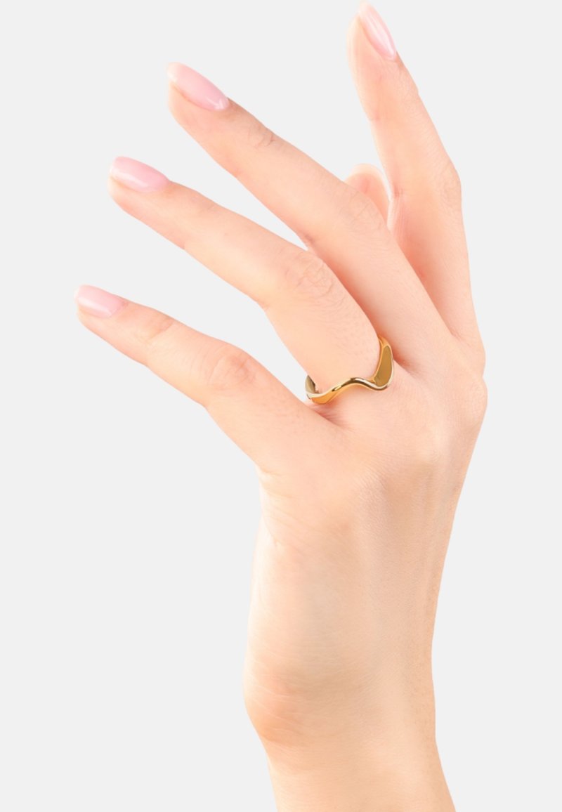 Anello in metallo dorato con un design ondulato, texture liscia e finitura lucida, mostrato su una mano con unghie di un rosa chiaro.