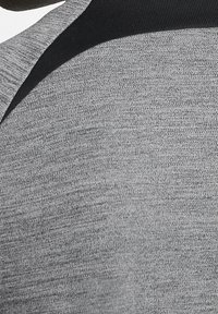 Gray athletic shirt with a textured fabric featuring a solid black collar and shoulder accents, designed for comfort and mobility.