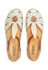 Sandales en cuir beige avec des découpes florales et un accent marron. Bords arrondis et cousus, avec une semelle intérieure rembourrée pour le confort.