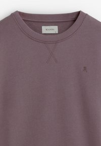 Paarse sweatshirt met een gestructureerde afwerking, voorzien van een geribbelde ronde hals en een klein geborduurd logo op de borst.