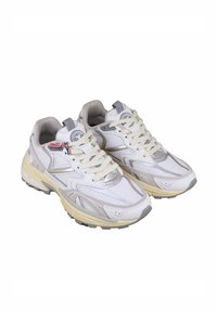 Sneaker atletiche bianche con tomaia in rete e sintetico, dettagli beige, chiusura con lacci e suola in gomma testurizzata. Logo visibile sulla linguetta.
