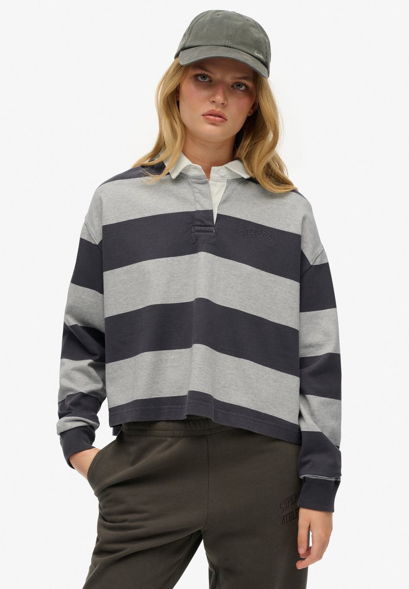 Gray and navy striped long-sleeve polo shirt with a white collar, featuring a small embroidered logo. Worn with olive green sweatpants.