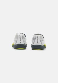 Baskets de sport légères en maille blanche avec des accents gris foncé et jaune fluo. Présentent un design profil bas et un talon texturé.